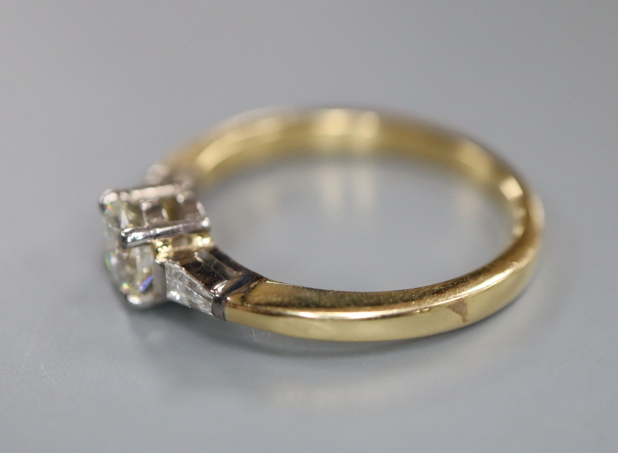 A modern 18ct gold and single stone diamond ring, with trapeze cut diamond set shoulders, size O, gross 3.7 grams,